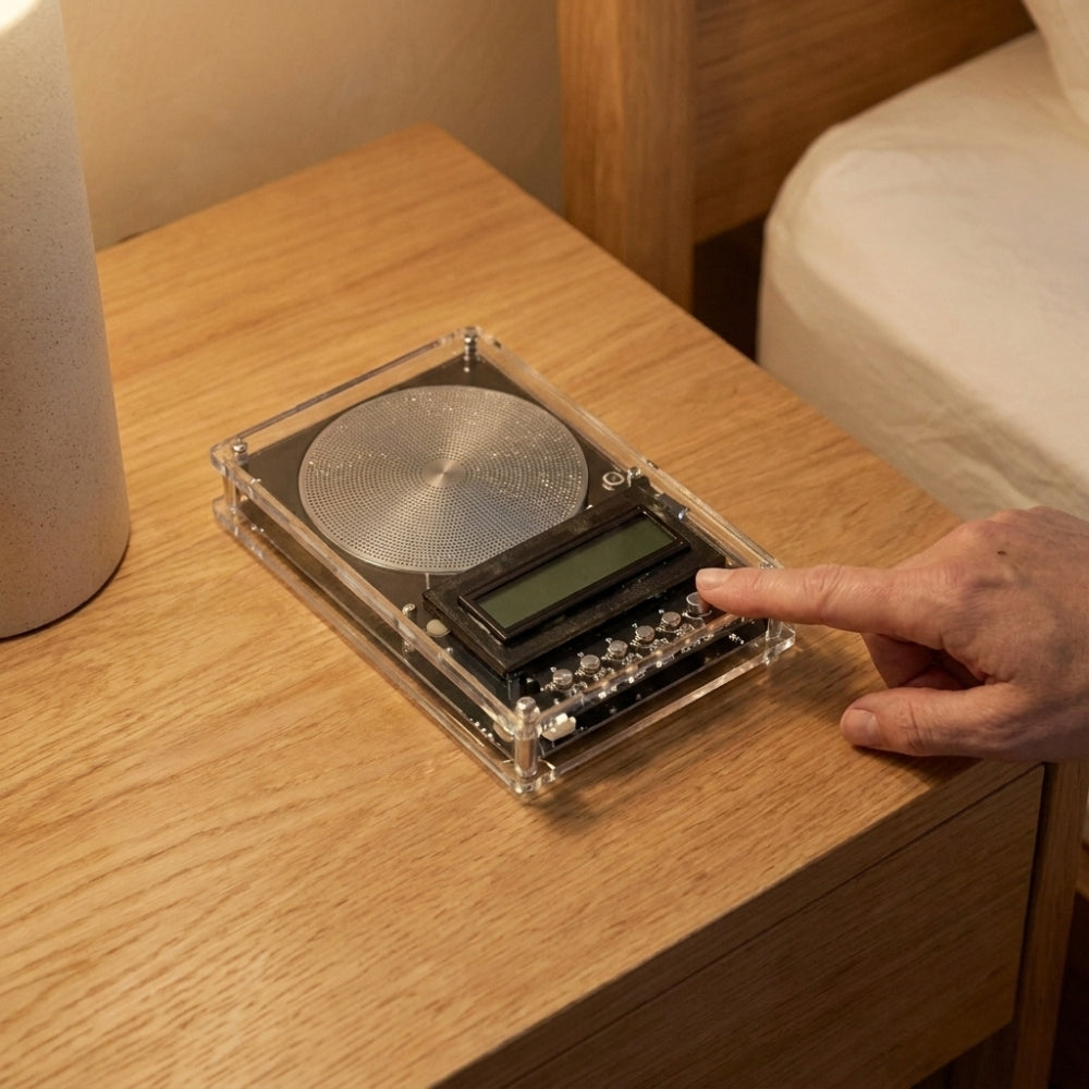 A finger pressing play on the Komfora device
